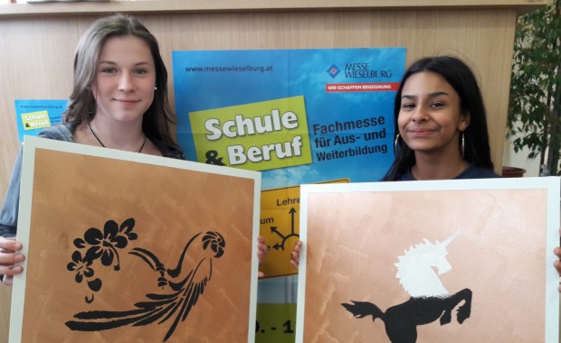 zwei Mädchen halten selbstgemalte Bilder