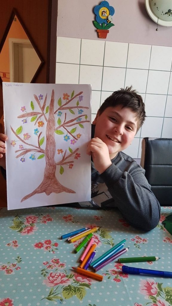 ein Bursch hält seinen gezeichneten Baum in die Kaera